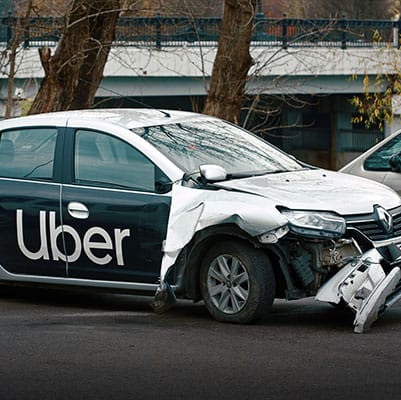 A rideshare Uber car displaying significant front-end damage, highlighting the consequences of an accident. - Brian Moore Injury Law