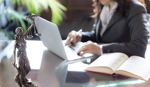Attorney in a suit seated at a desk, focused on her laptop, exemplifying a modern work environment. - Brian Moore Injury Law